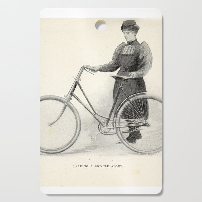 "Leading a Bicycle About" from "Bicycling for Ladies" by Maria E. Ward, 1896 Cutting Board