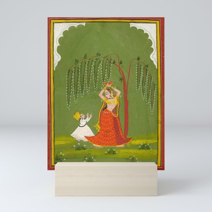 A female attendant is standing in tribhanga pose under a tree. A small child vies for her attention. Mini Art Print